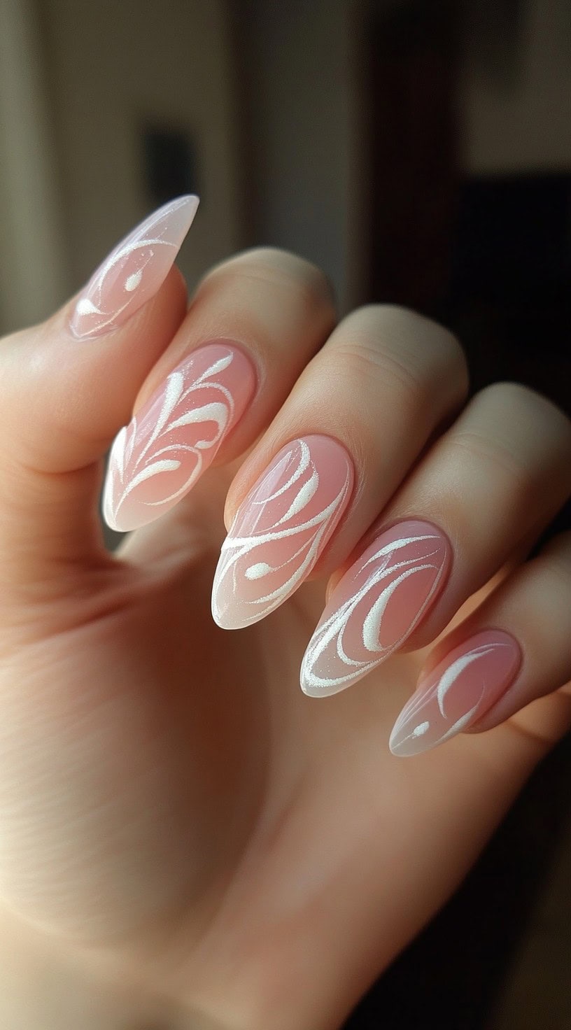 A set of almond-shaped nails with a sheer pink base, featuring delicate white swirl patterns in a flowing design.