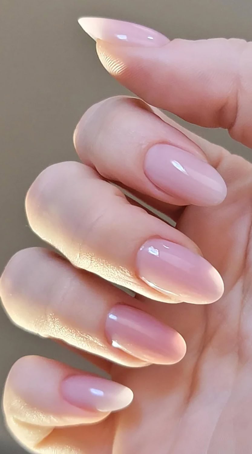 Close-up of glossy pink almond-shaped gel nails in natural lighting, showcasing a smooth and professional finish.