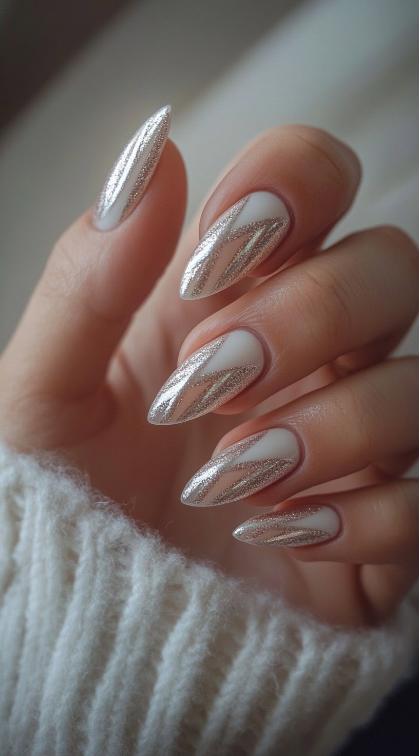 A close-up of almond-shaped nails with a white base and intricate silver chrome accents forming modern, abstract patterns.