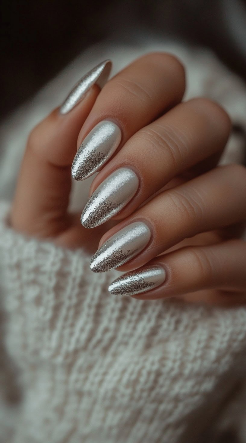 Almond-shaped nails featuring a metallic silver base that gradually fades into fine glitter at the tips, creating a soft gradient effect.