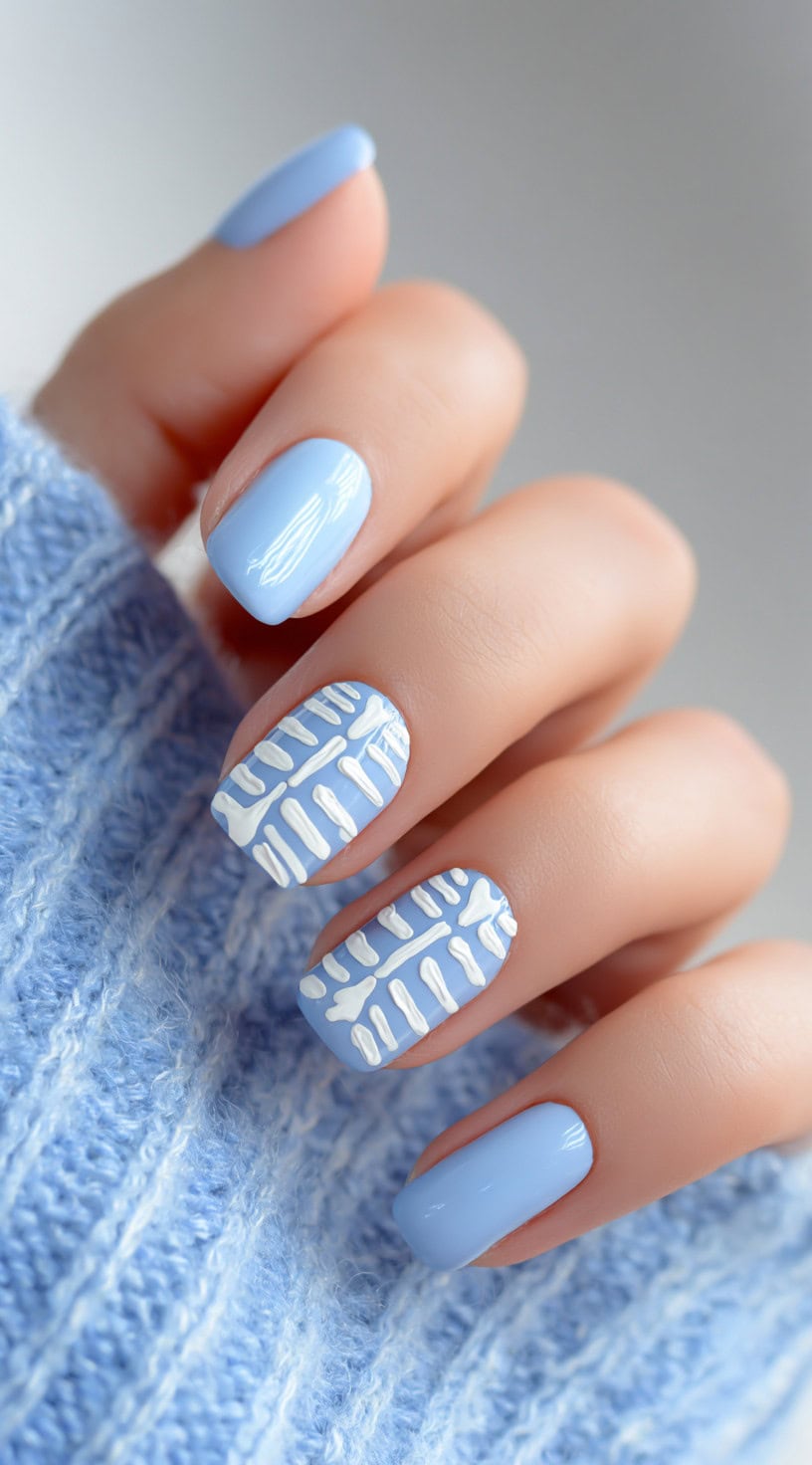 Light blue square nails with white skeleton ribcage patterns on the middle and ring fingers, paired with plain pastel blue nails.