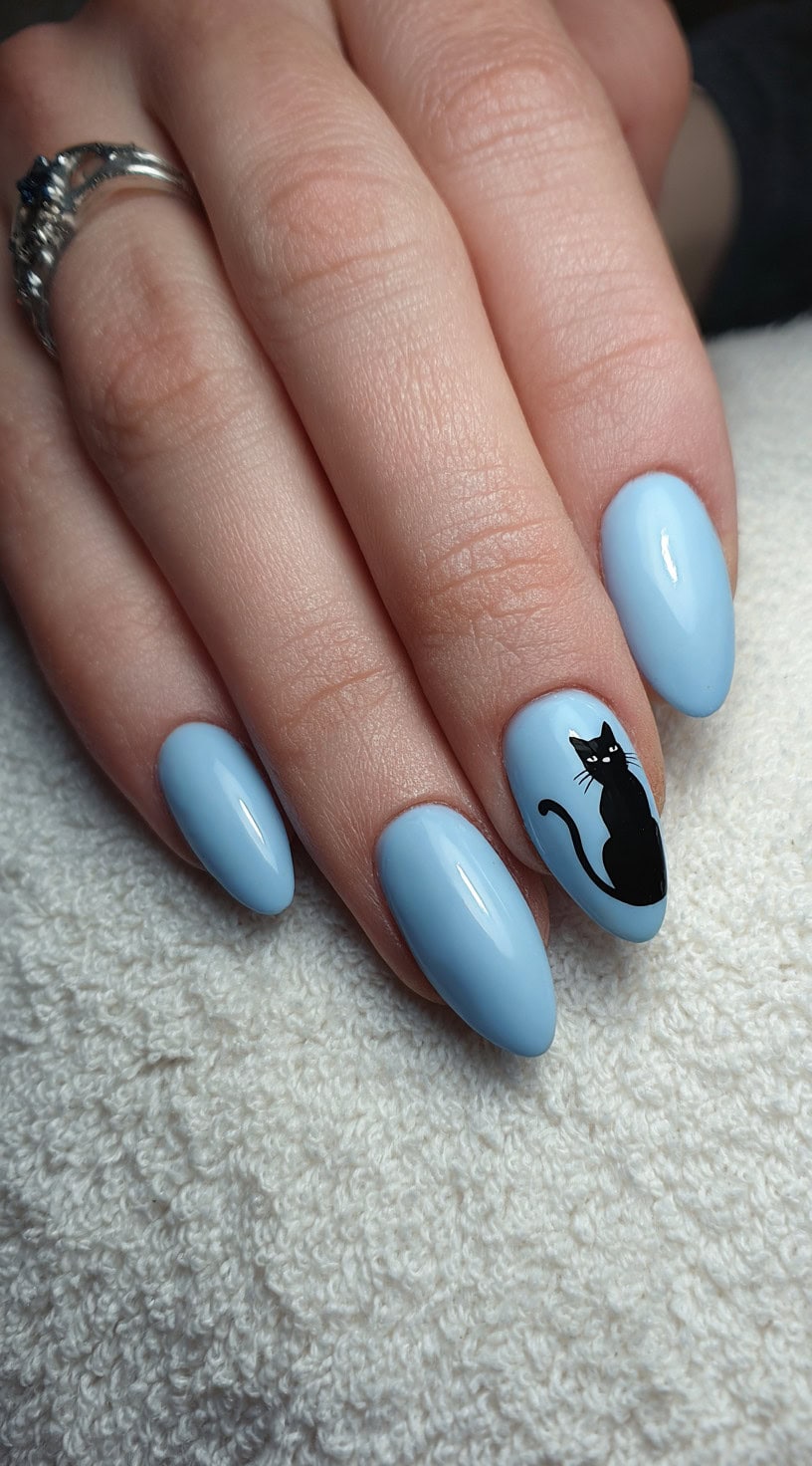 Almond-shaped nails painted pastel blue, with one accent nail showcasing a sleek black cat silhouette.