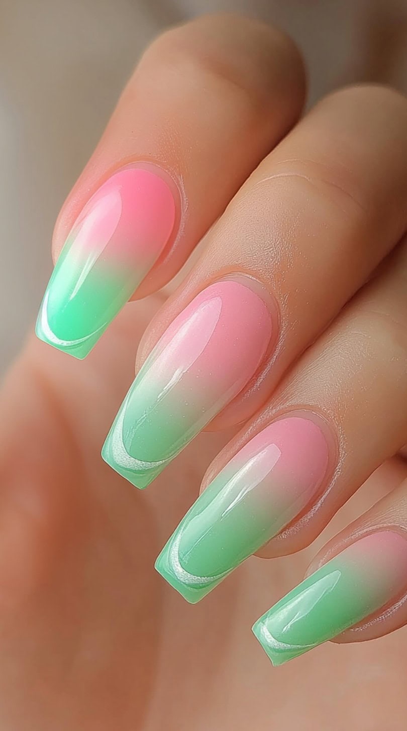 A hand with square nails in a glossy pink and green ombre with a smooth, candy-like finish.