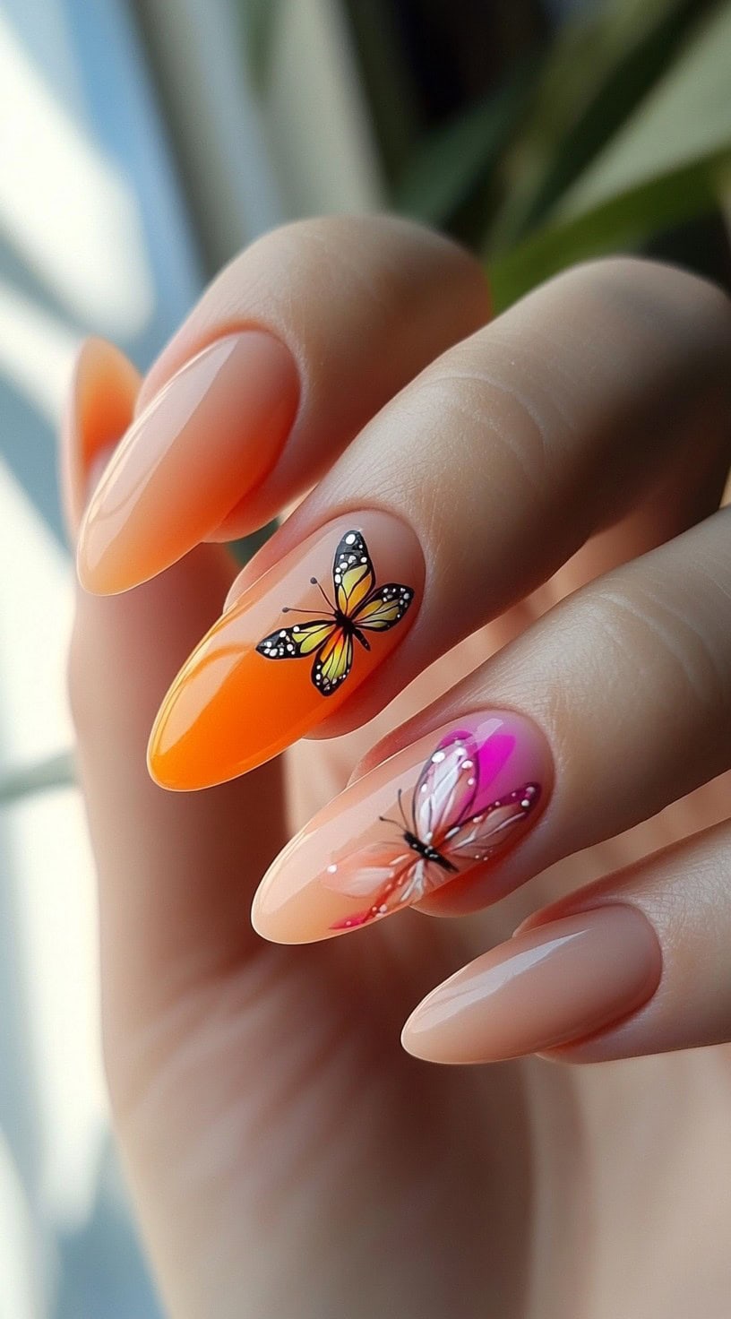 Almond-shaped nails with sheer nude and orange bases, decorated with delicate butterfly decals in pink and yellow.