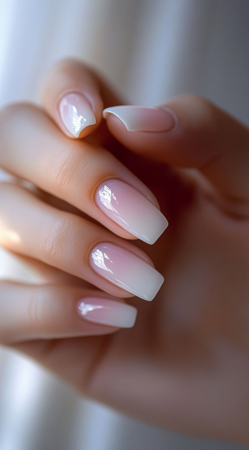 A close-up of medium-length, square-shaped nails with a seamless transition from soft pink to milky white in an ombre effect.