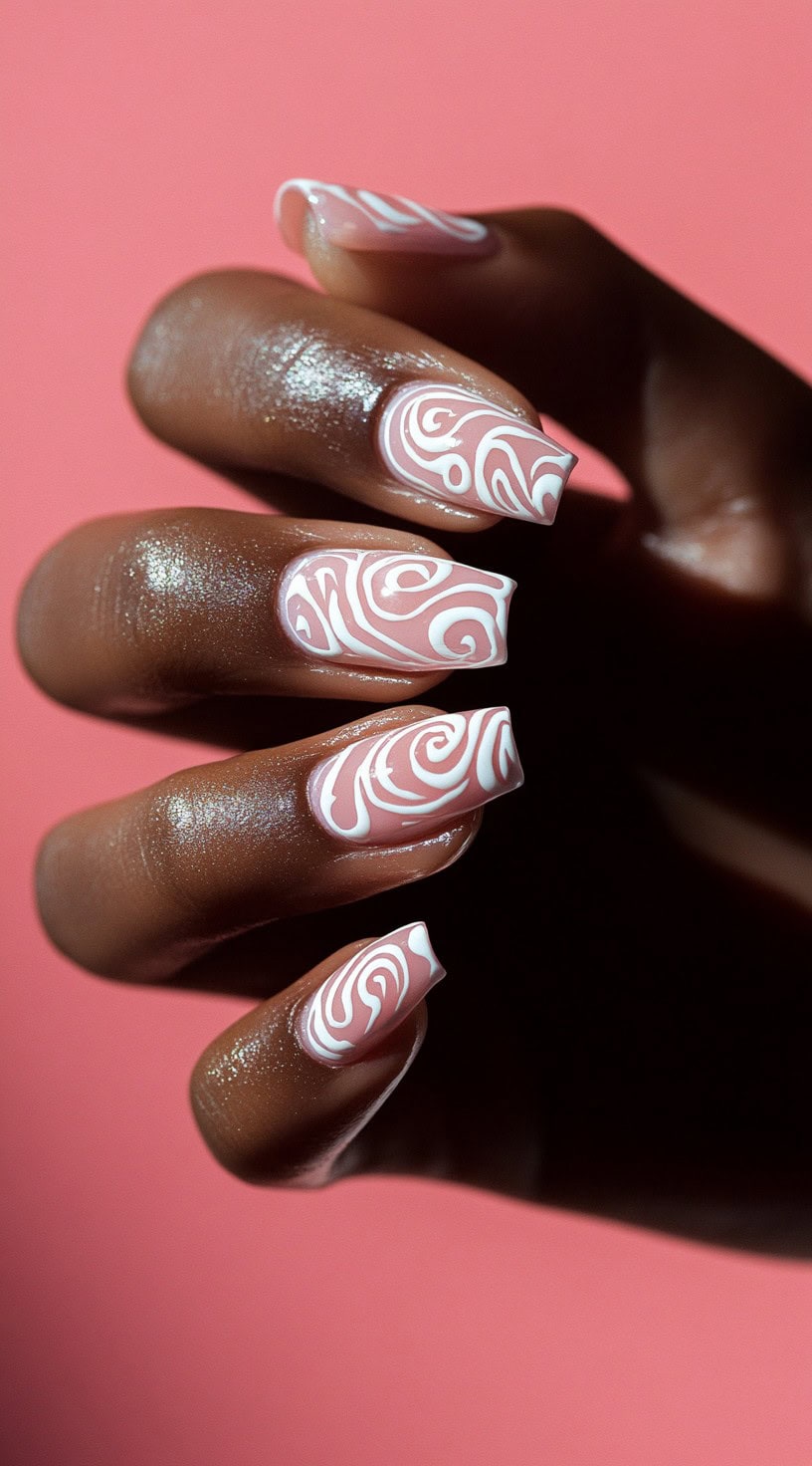 A set of coffin-shaped nails with a soft pink base and intricate white swirl patterns, creating a romantic and modern design.