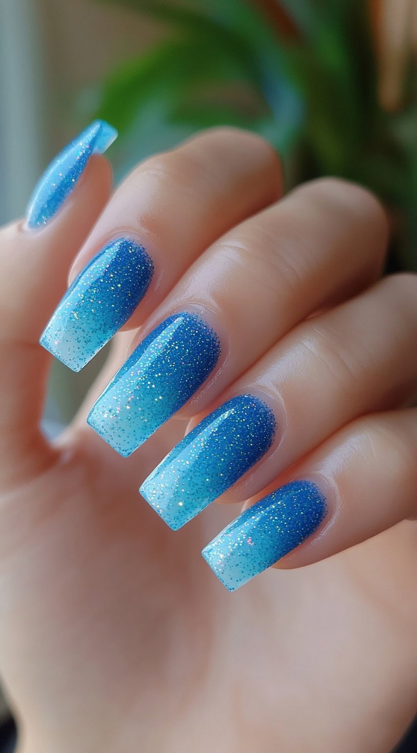 Square-shaped nails featuring a smooth ombre from bright aqua to deep cobalt blue with holographic glitter.