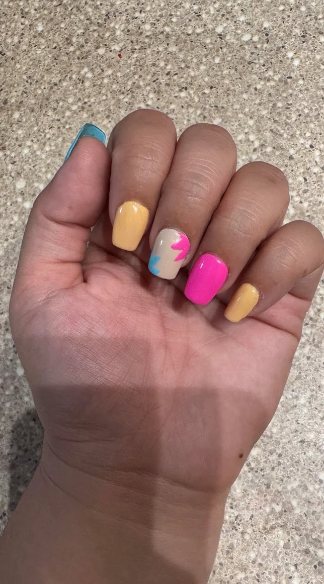 Squoval nails for short nail beds styled in bright pink and yellow with a colorful lightning bolt accent, offering a fun and balanced look for wider nail shapes.