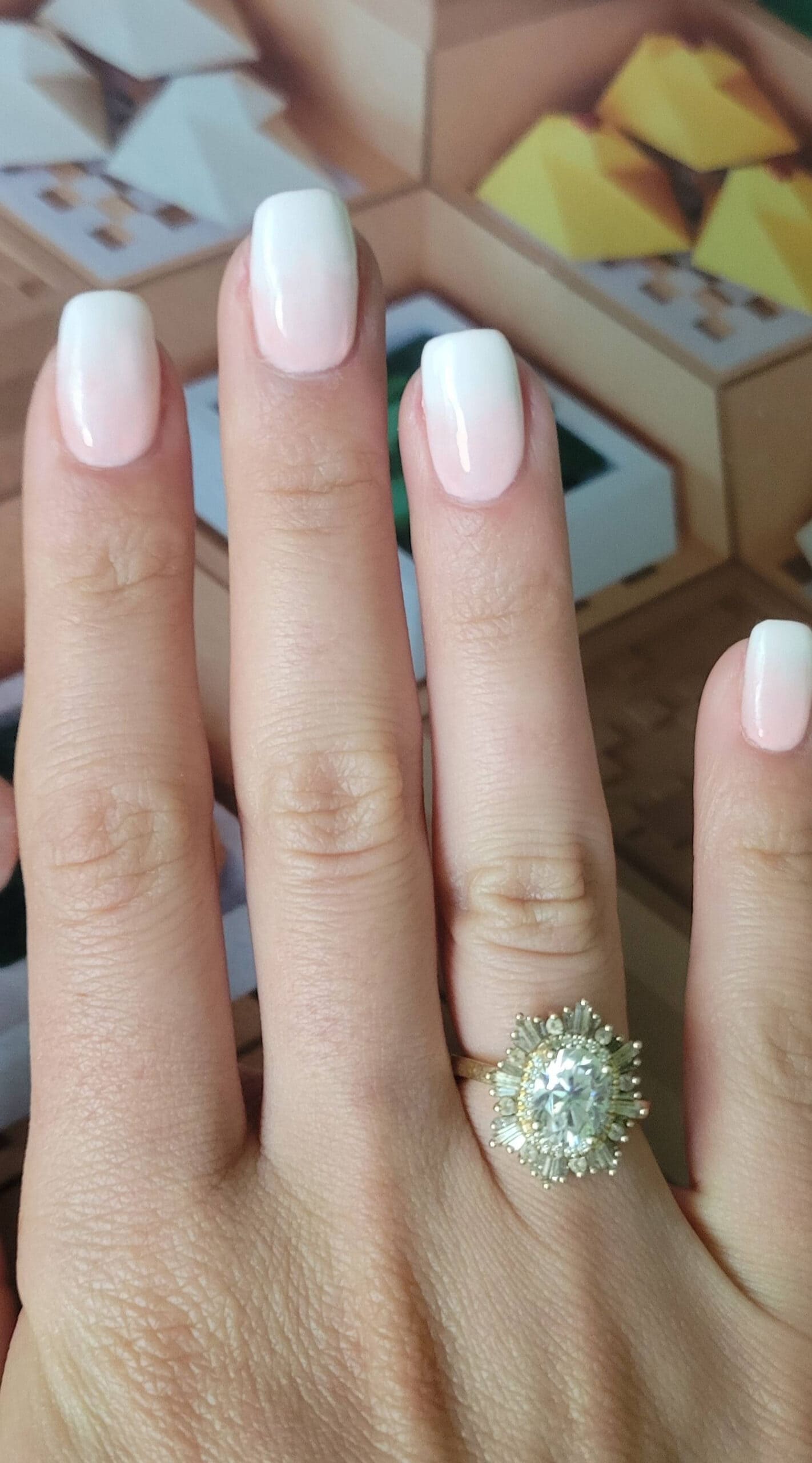 Long fingers with soft pink ombre squoval nails, accented by a statement ring.