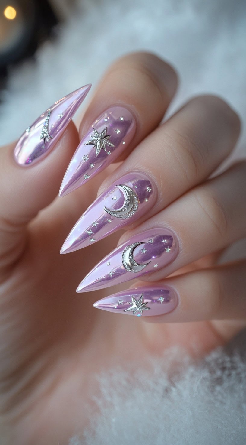Light pink stiletto chrome nails with silver moon and star embellishments over a pearlescent purple-pink base.