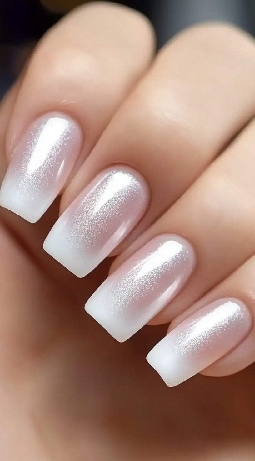 A set of square-shaped nails featuring a soft French fade with a sheer pink base and delicate silver glitter dusted along the tips.