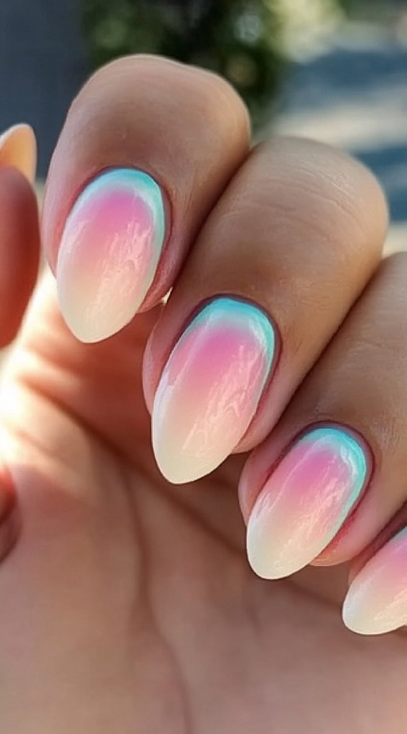 Almond-shaped nails with a soft gradient from pink to turquoise, resembling a serene sunset sky.