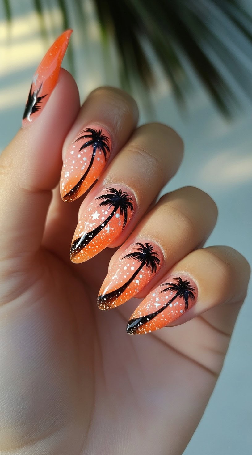 Almond-shaped nails with an orange gradient base and black palm tree silhouettes, accented with white star-like dots.