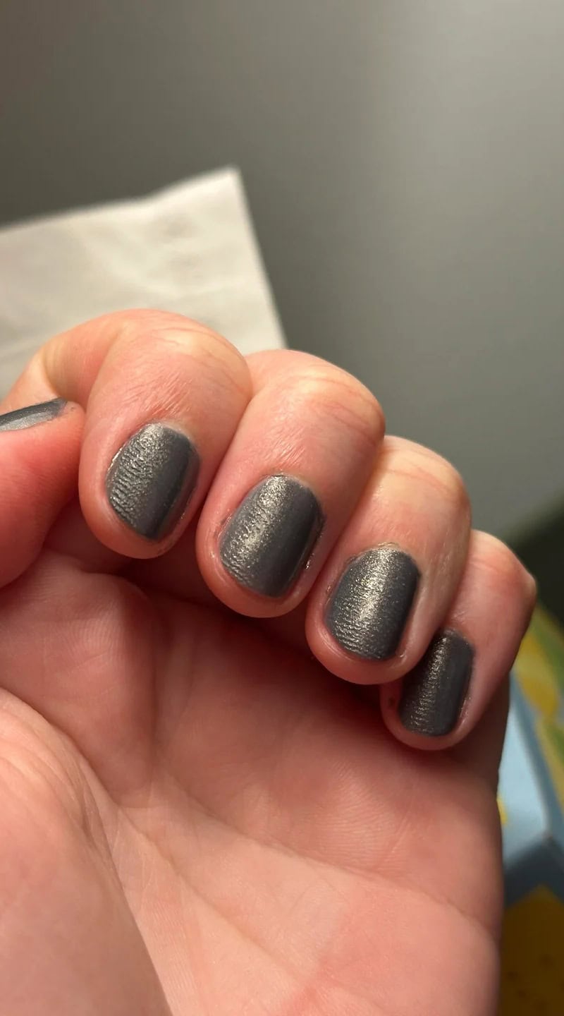 Grey painted nails with a noticeable smudged texture and fine fingerprint impressions.