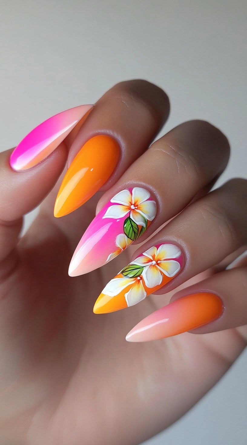 Long stiletto nails featuring a tropical pink and orange gradient with hand-painted white plumeria flowers and green leaves.