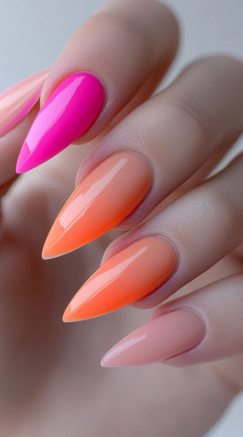 Stiletto nails in bright blocks of color, ranging from neon pink to orange and peach, finished with a high gloss.