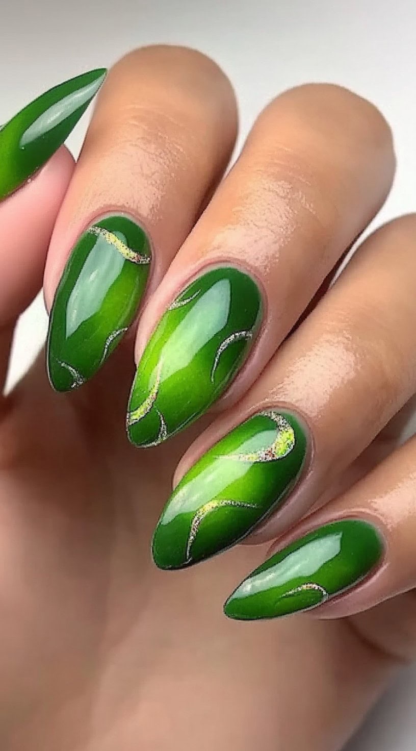 A close-up of almond-shaped nails with a bright green glossy base, adorned with fine gold glitter lines forming abstract curves.