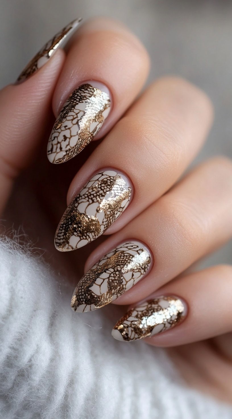 Almond-shaped nails with a white and gold cracked lace pattern resembling tooled leather designs.