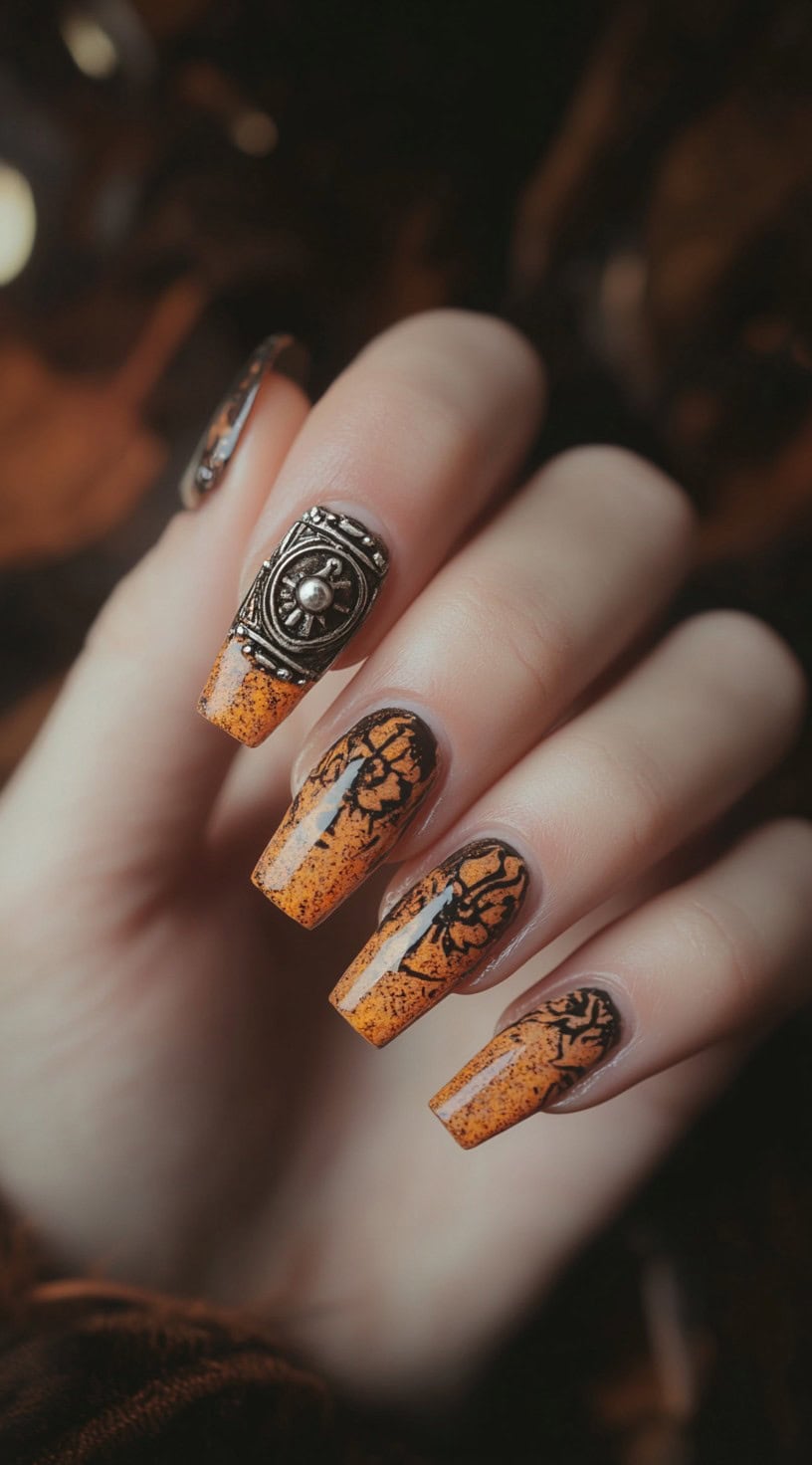 Square-shaped nails with an orange gradient base, black Western floral designs, and a large silver concho accent on one nail.