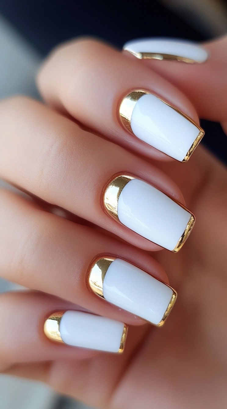 A set of square-shaped nails with crisp white tips and luxurious gold metallic detailing along the edges.