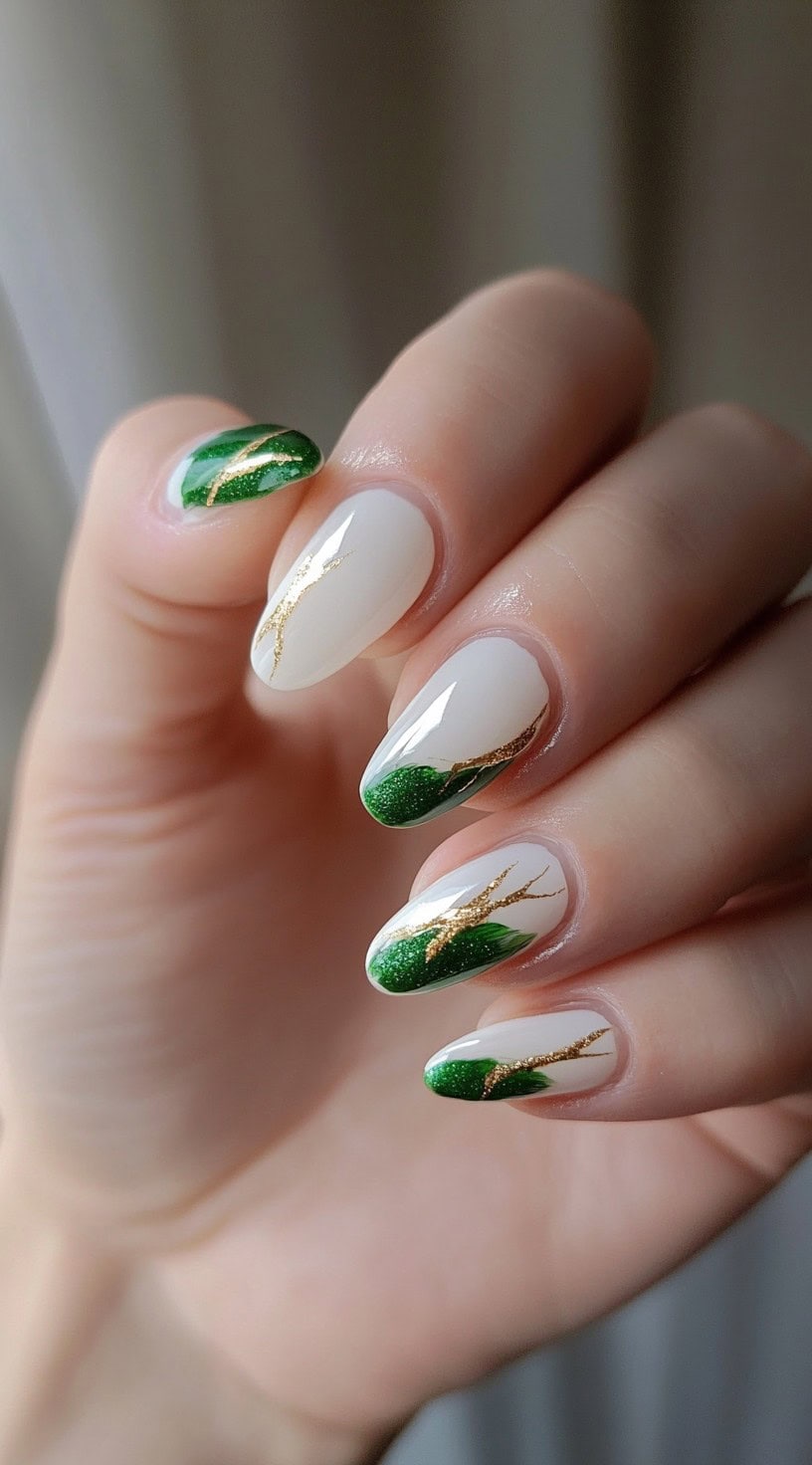 A set of almond-shaped nails featuring a white base with deep green brushstrokes and fine gold detailing for an artistic, modern touch.