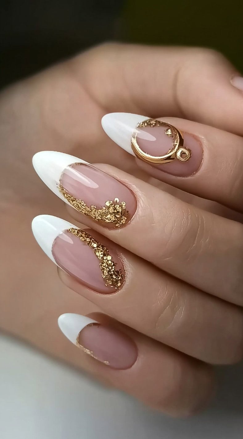 Almond-shaped nails with classic white French tips, embellished with scattered gold foil and a raised gold metal ring accent on the ring finger.