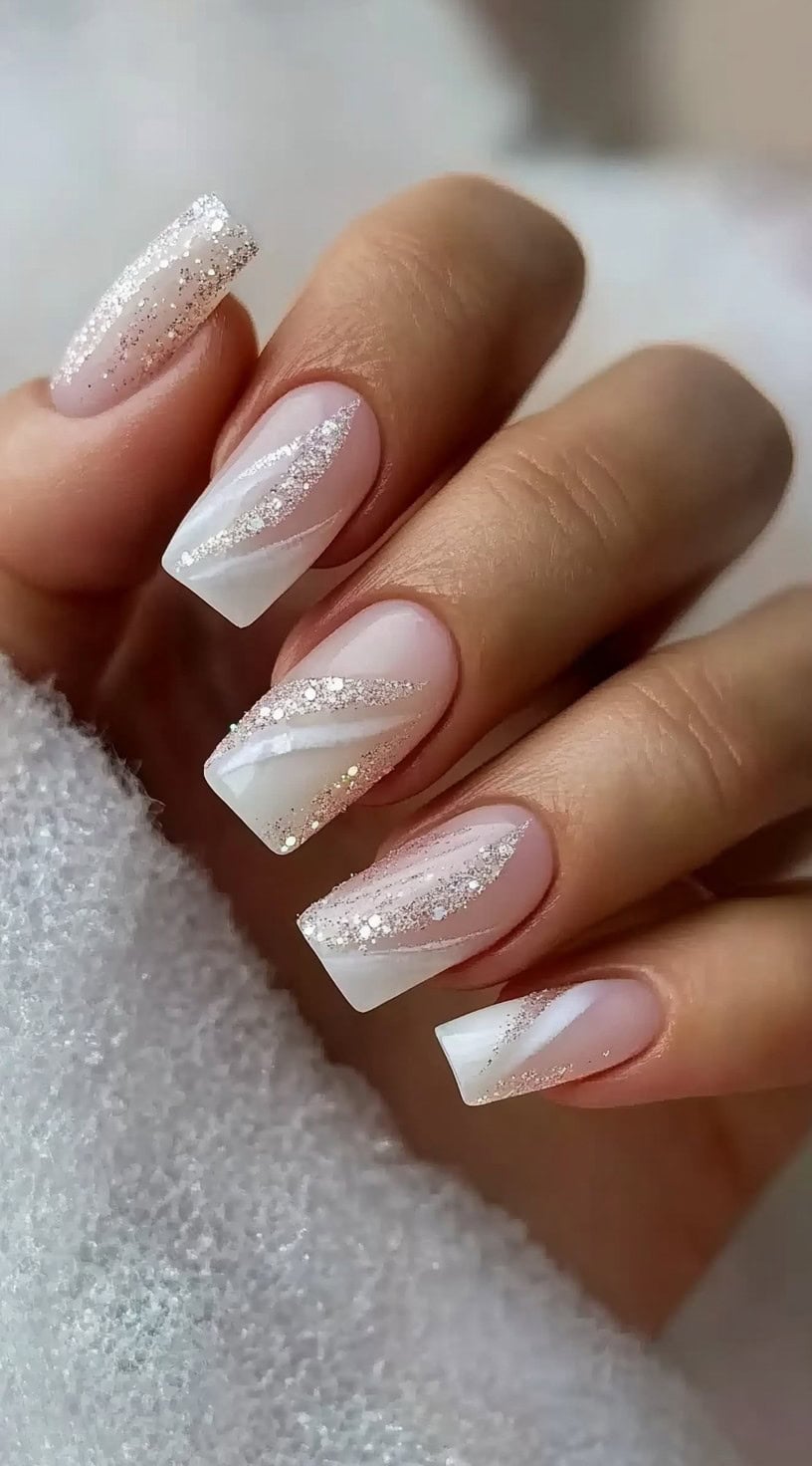 Square-shaped nails with a nude-to-white gradient base, featuring delicate swirling glitter accents.