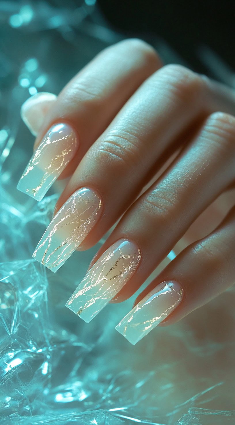 A close-up of square-shaped nails featuring a translucent white marble effect with delicate gold vein detailing.