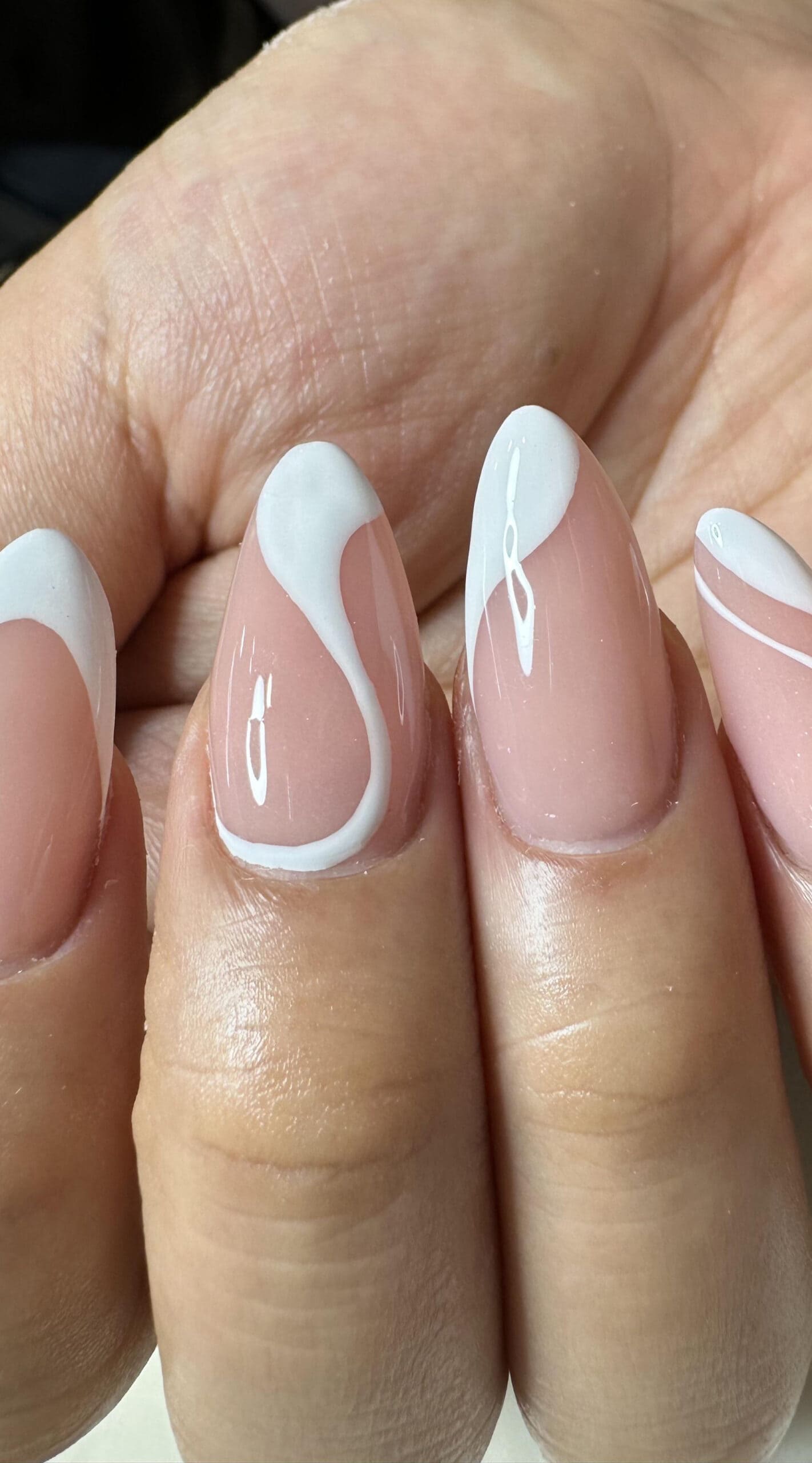 Close-up of almond-shaped acrylic nails with a glossy pink base and minimal white swirl accents.