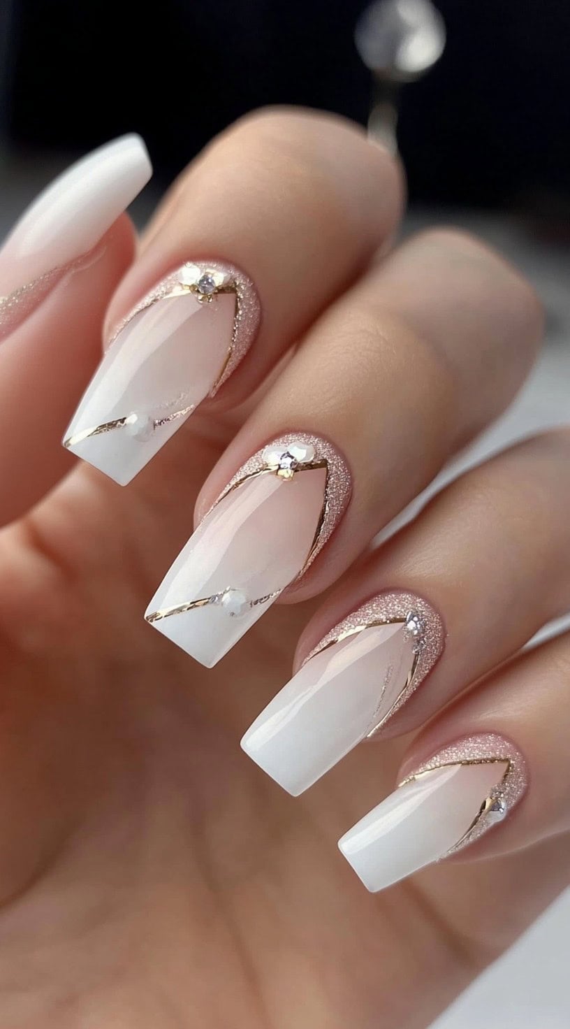 Square white nails with soft V-shaped French tips, pink glitter outlines, and rhinestone accents.