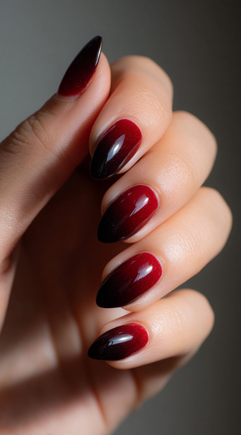 A close-up of almond nails with a smooth gradient from deep black cherry at the tips to vibrant wine red near the cuticles.