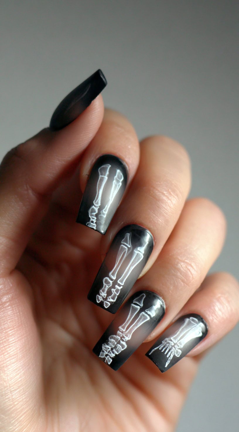 Long square nails with a soft black-to-clear ombre base and crisp white bone outlines creating the look of an X-ray scan.